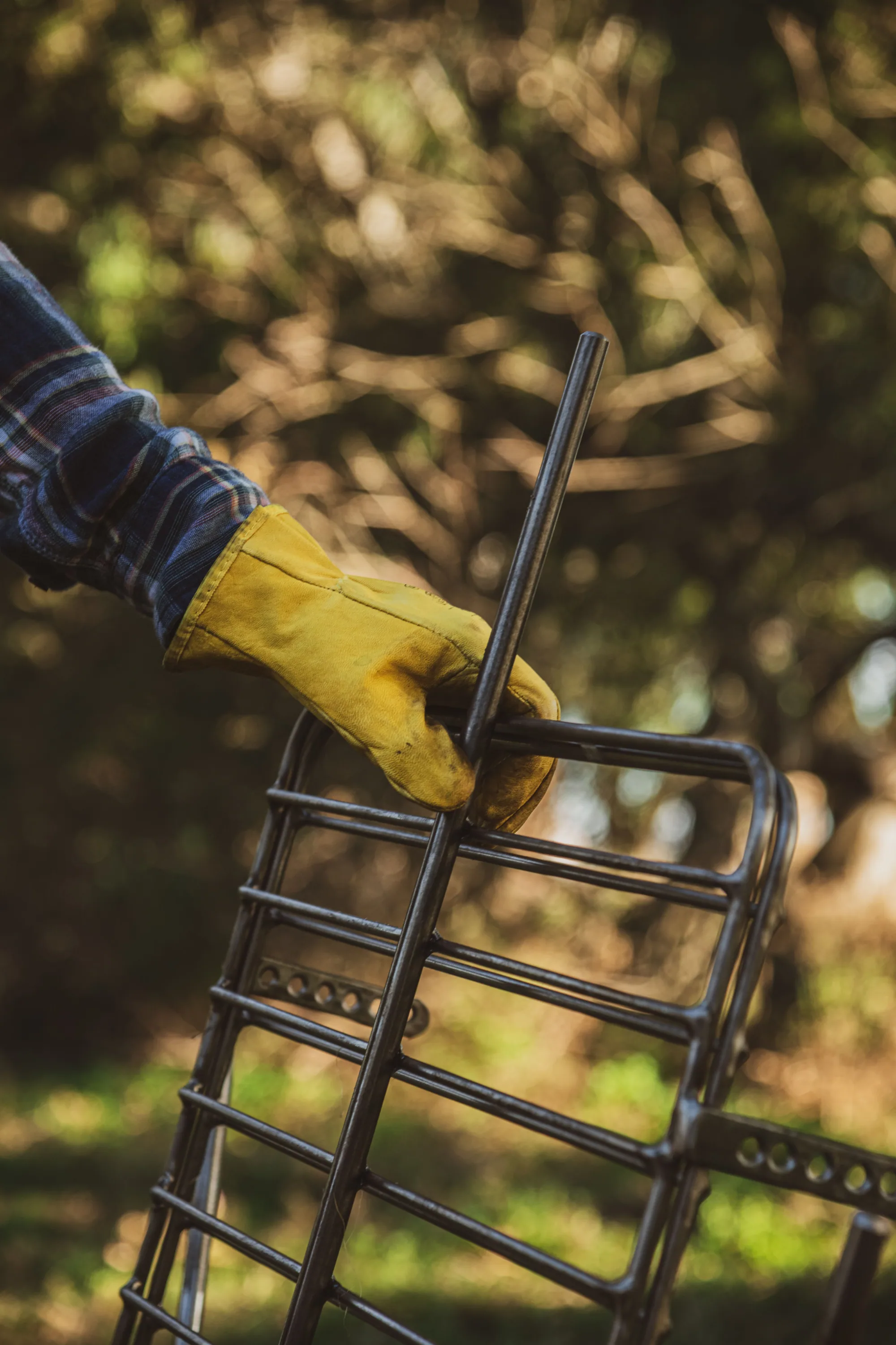 A gloved hand holding a Sostiene asador frame