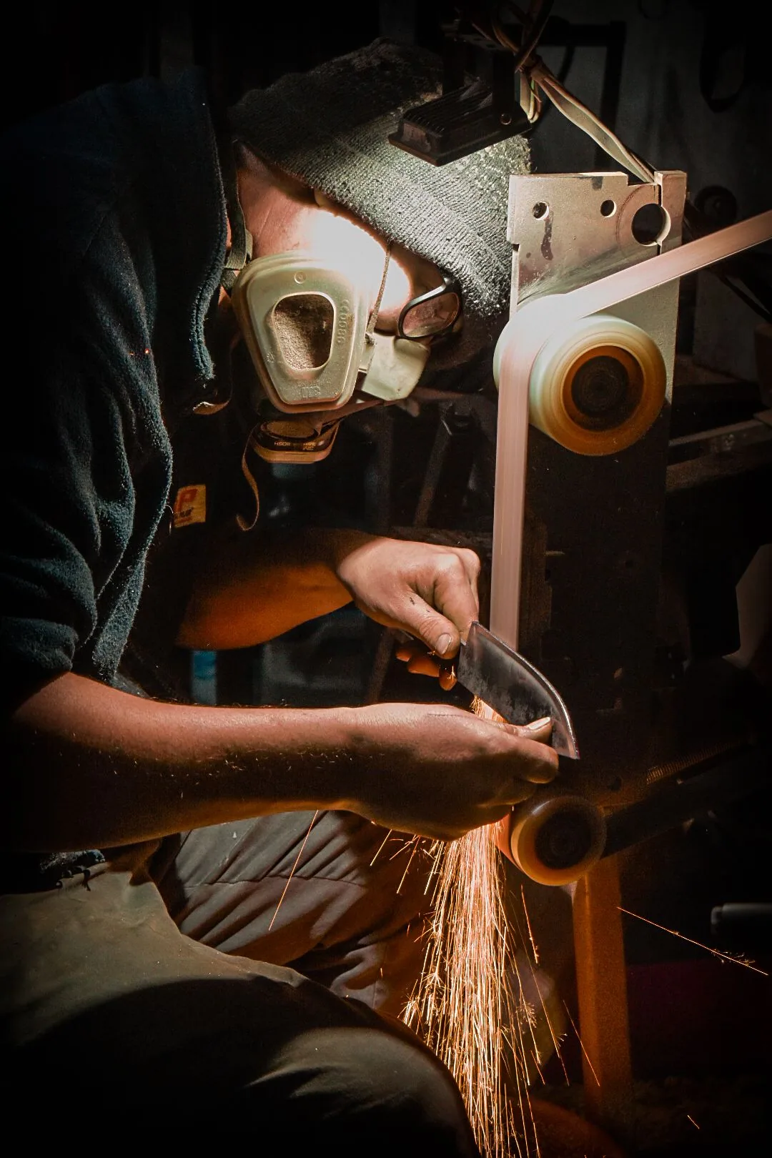 A craftsman grinding a blade, sparks flying, in the workshop