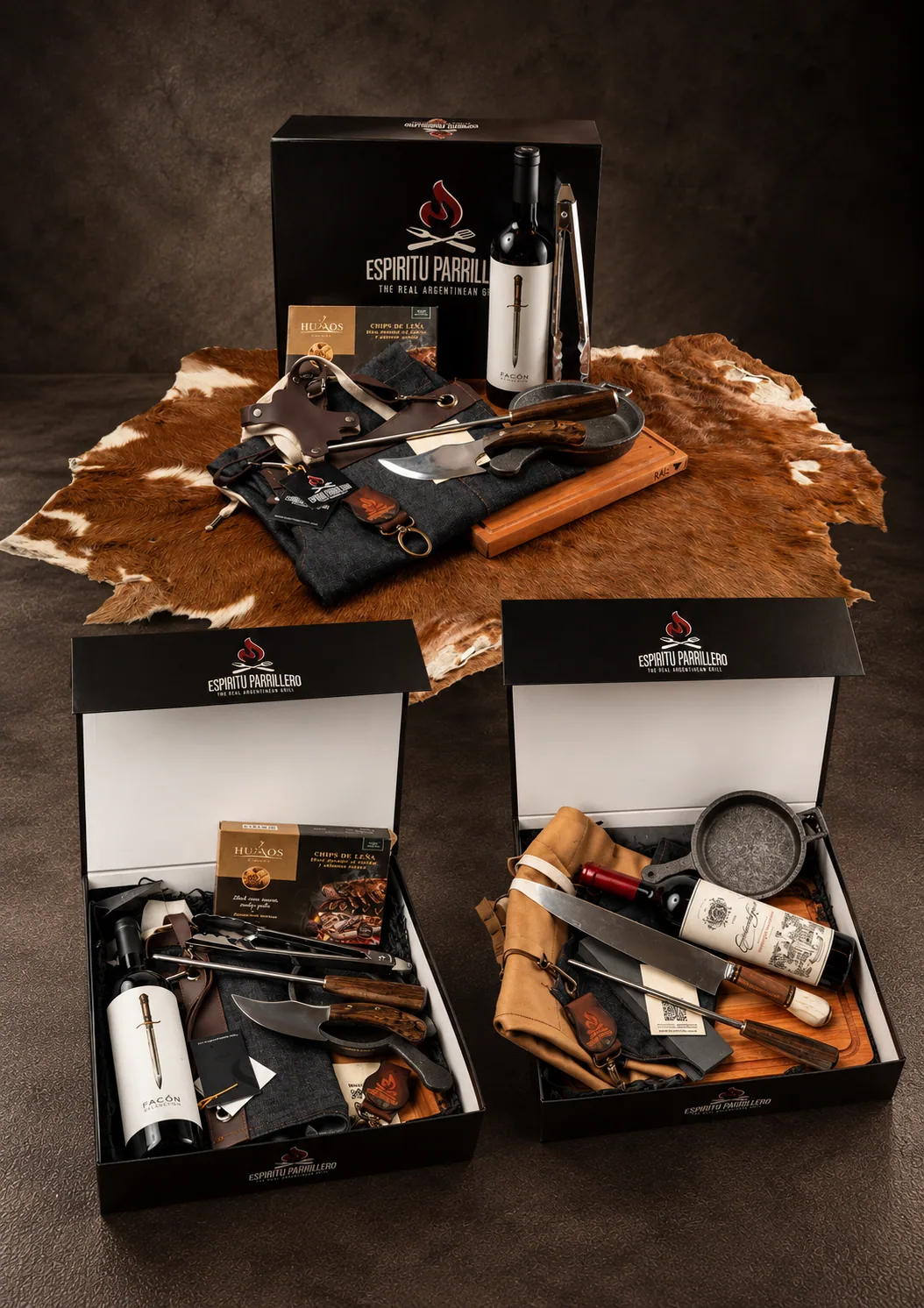 Espíritu Parrillero premium gift boxes, open and filled, on dark stone