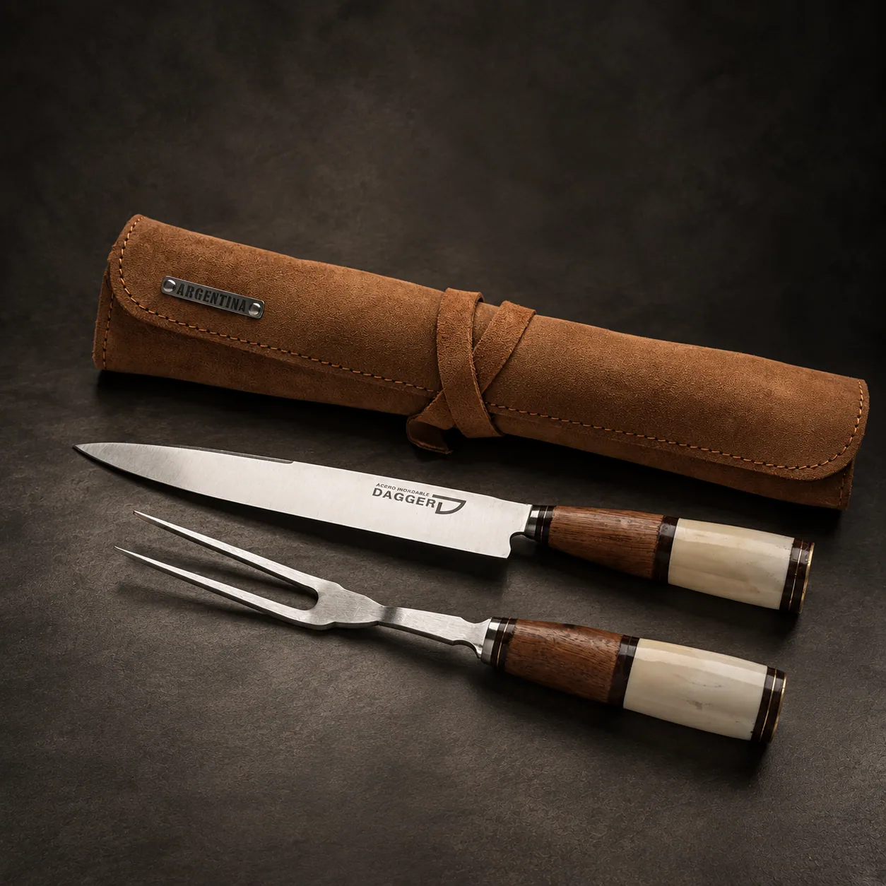 The Kit Chaman 2P knife and carving fork in their leather roll, on dark stone