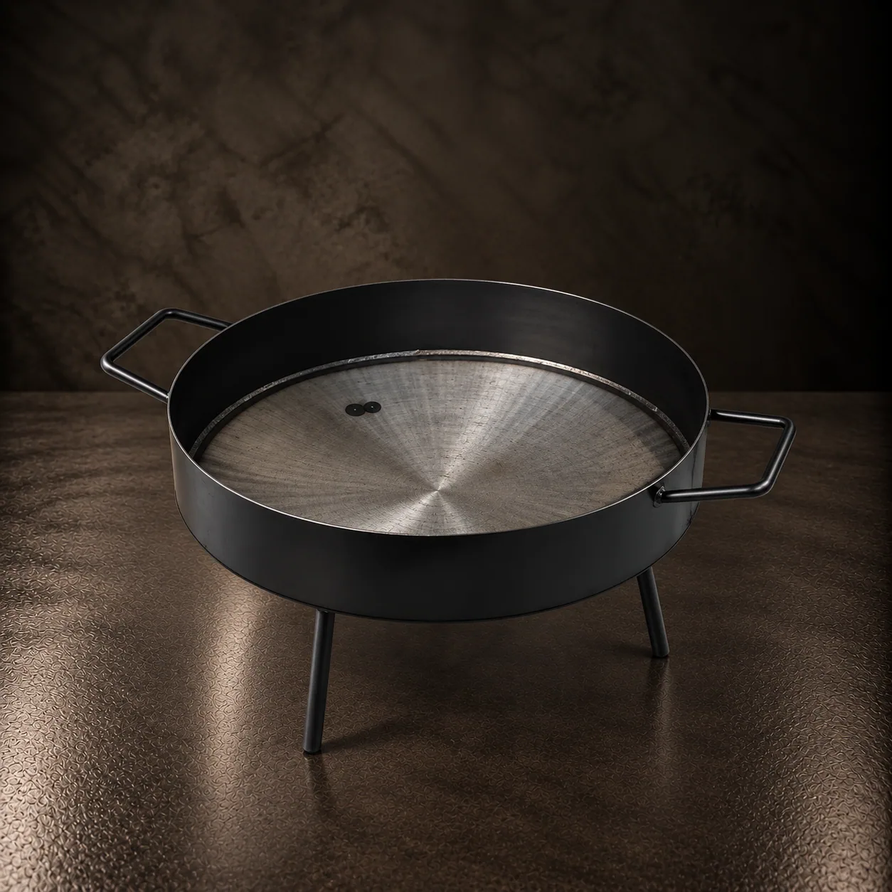 The iron plow disc on its tripod, on dark stone