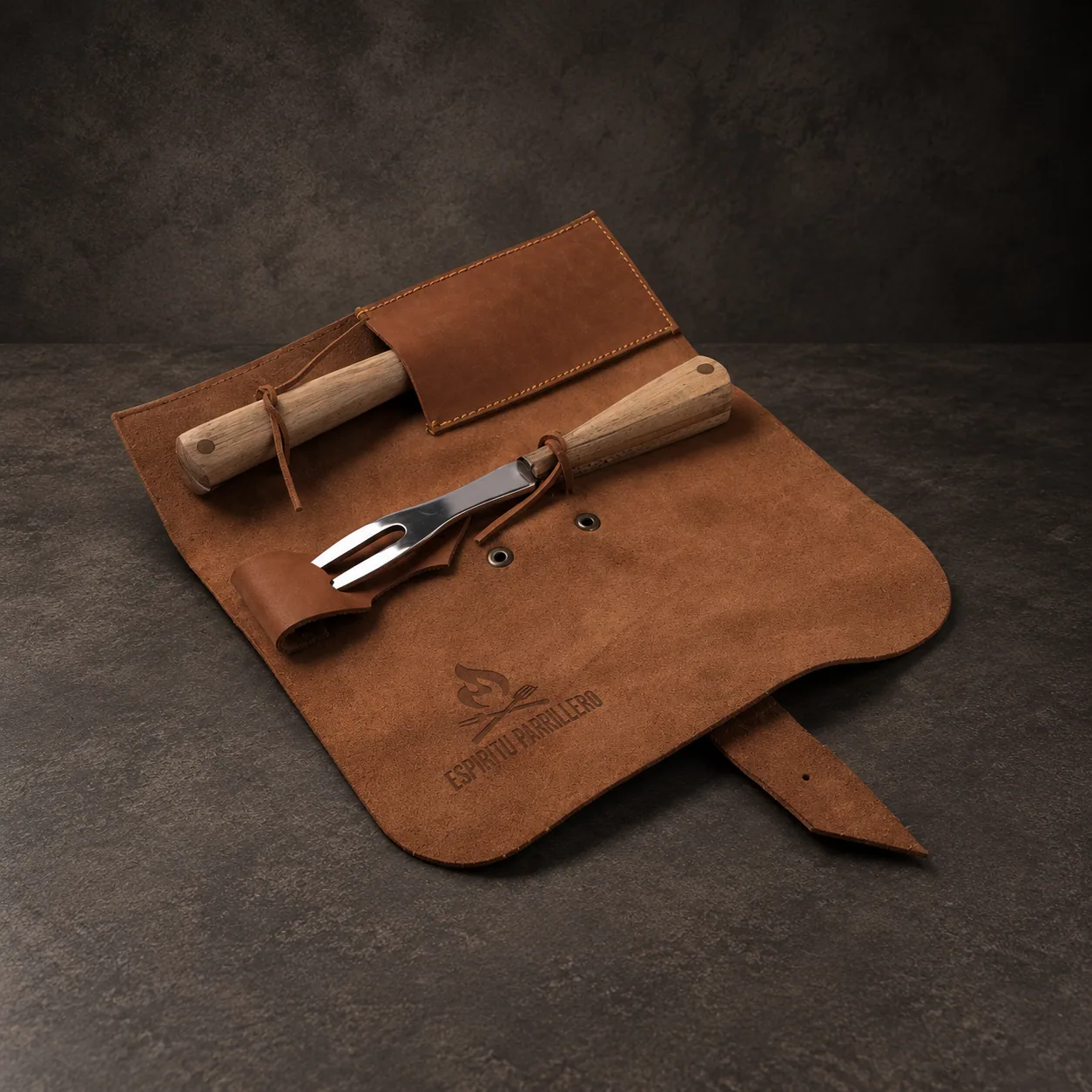 The pocket cutlery kit open on its leather roll, knife and fork out, on dark stone