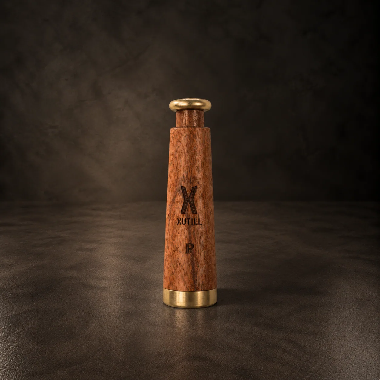 The wooden pepper grinders with their brass detail, on dark stone