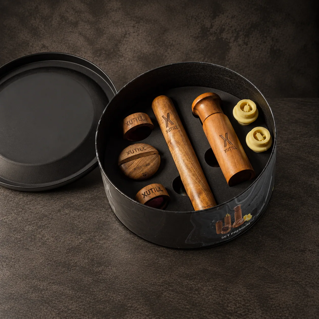 The Xutill premium set in its round tin, grinders and shakers inside, on dark stone